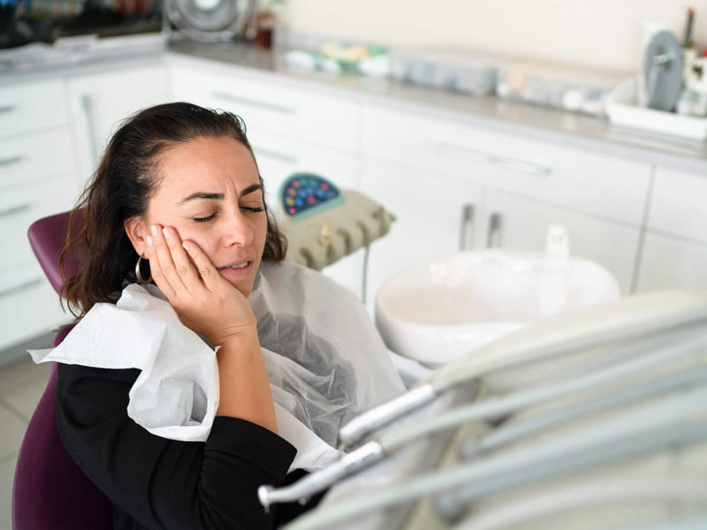 women with jaw pain sitting in operating chair