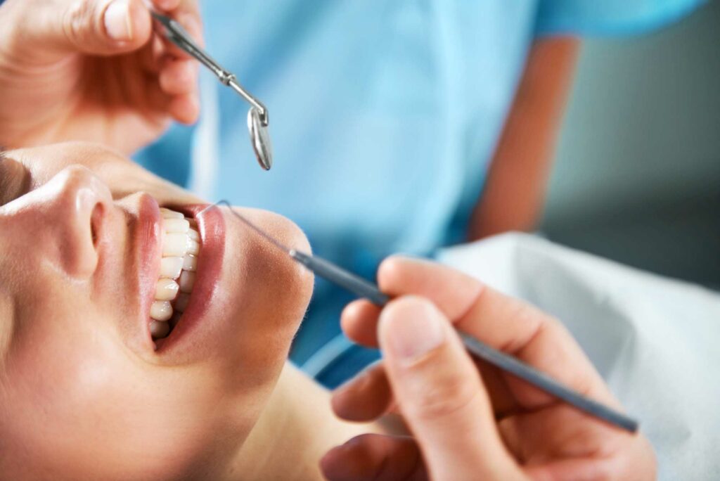 woman smiling as doctor checks her teeth