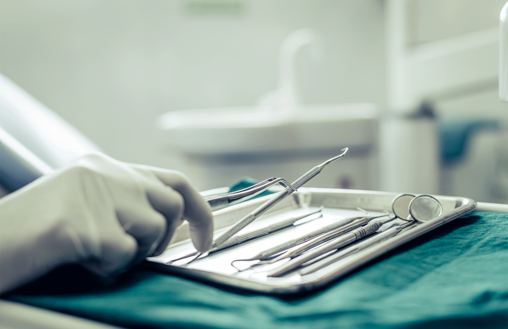 doctors tools on tray with a hand holding one of them